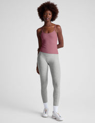 model is wearing a pink midway length tank top with adjustable straps and gray leggings against a plain background.