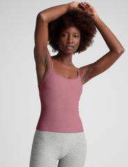 model is wearing a pink midway length tank top with adjustable straps and gray leggings against a plain background.