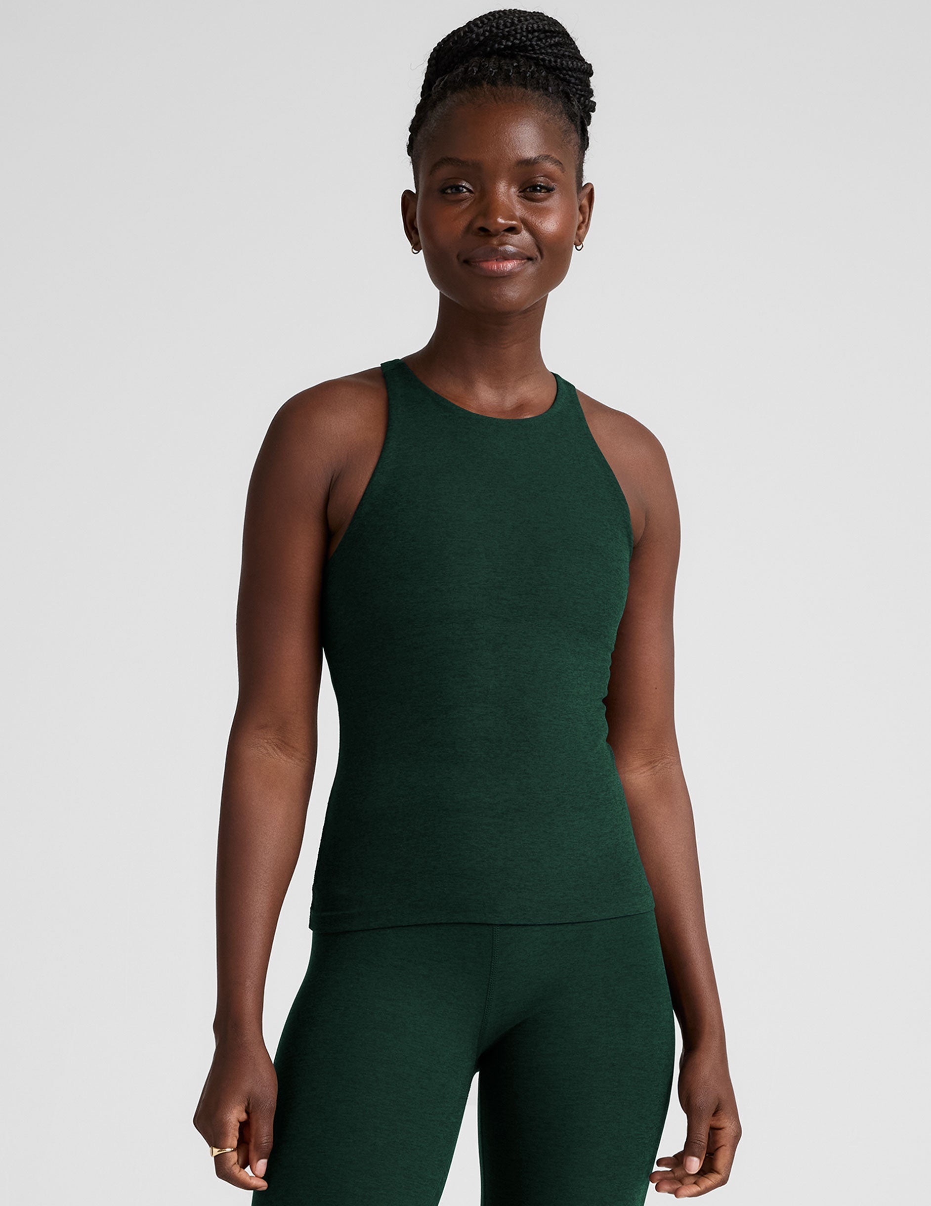 model is wearing a green high neck full length racerback tank top and leggings against a plain background.