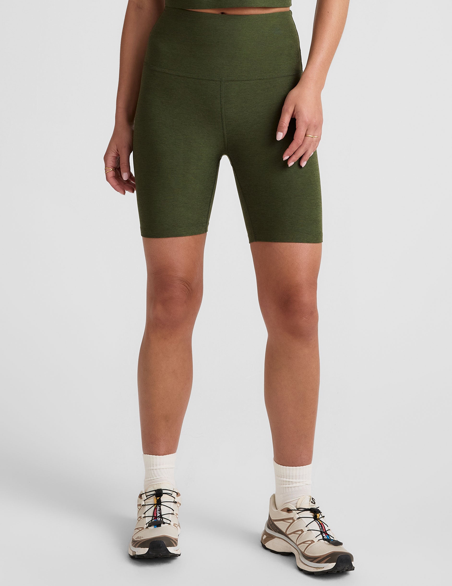 model is wearing green high-waisted 7" inseam biker shorts. 