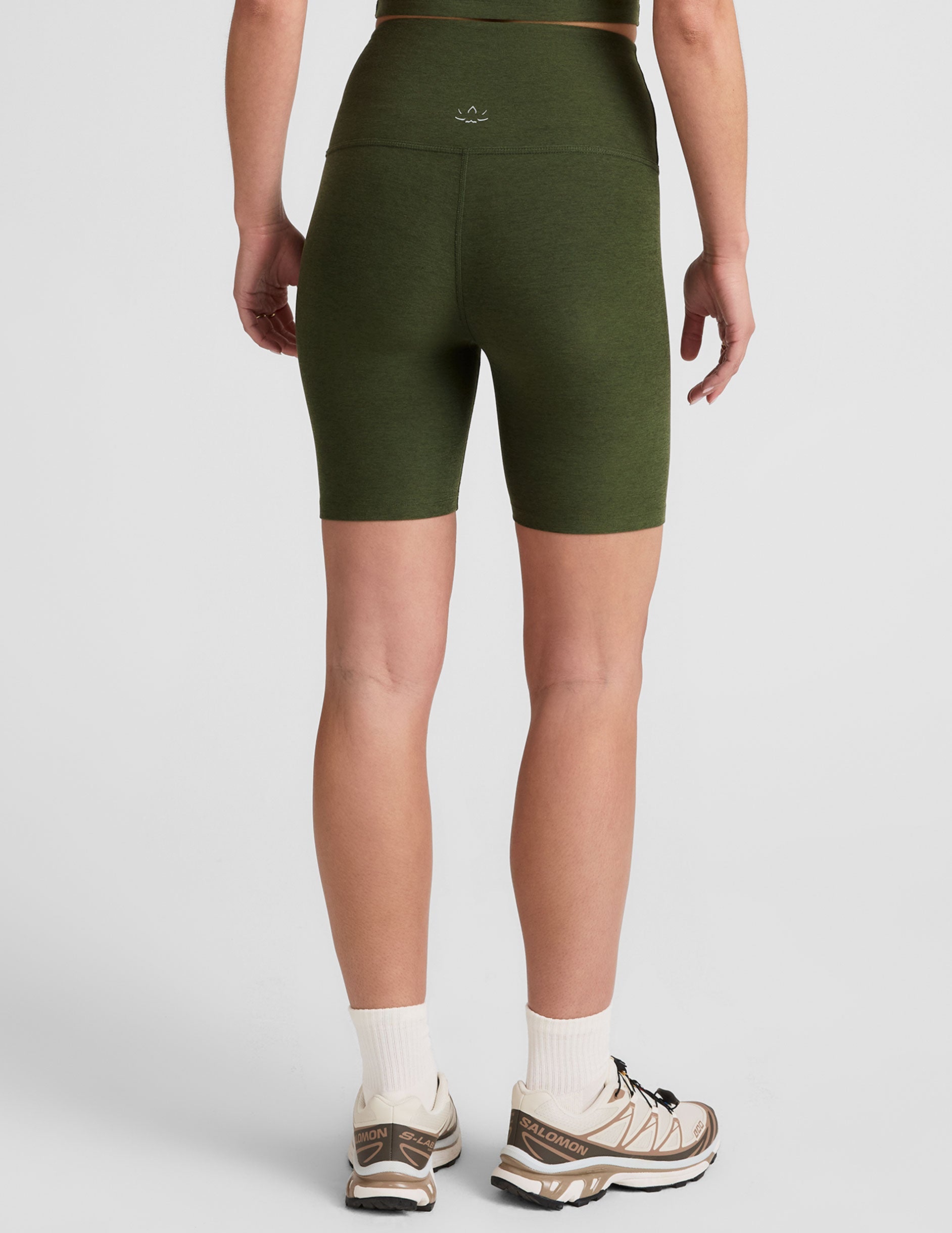 model is wearing green high-waisted 7" inseam biker shorts. 