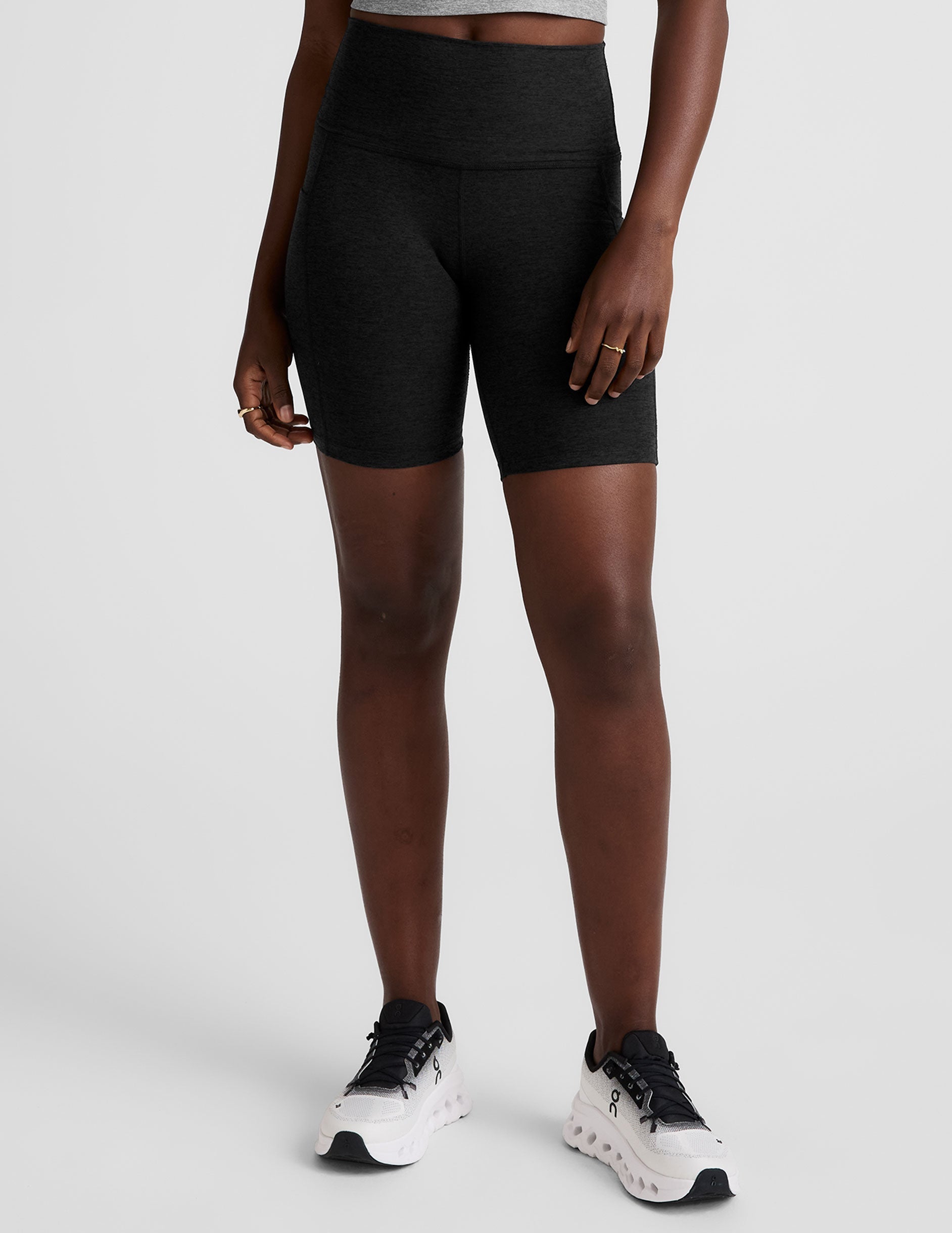 model wearing black 7" inseam biker shorts with pockets on a plain background. 