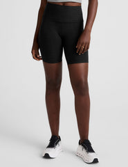model wearing black 7" inseam biker shorts with pockets on a plain background. 