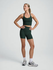 woman wearing a green v-neck cropped tank and green high-waisted 5" biker shorts on a plain background. 