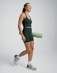 woman wearing a green v-neck cropped tank and green high-waisted 5" biker shorts on a plain backgroun