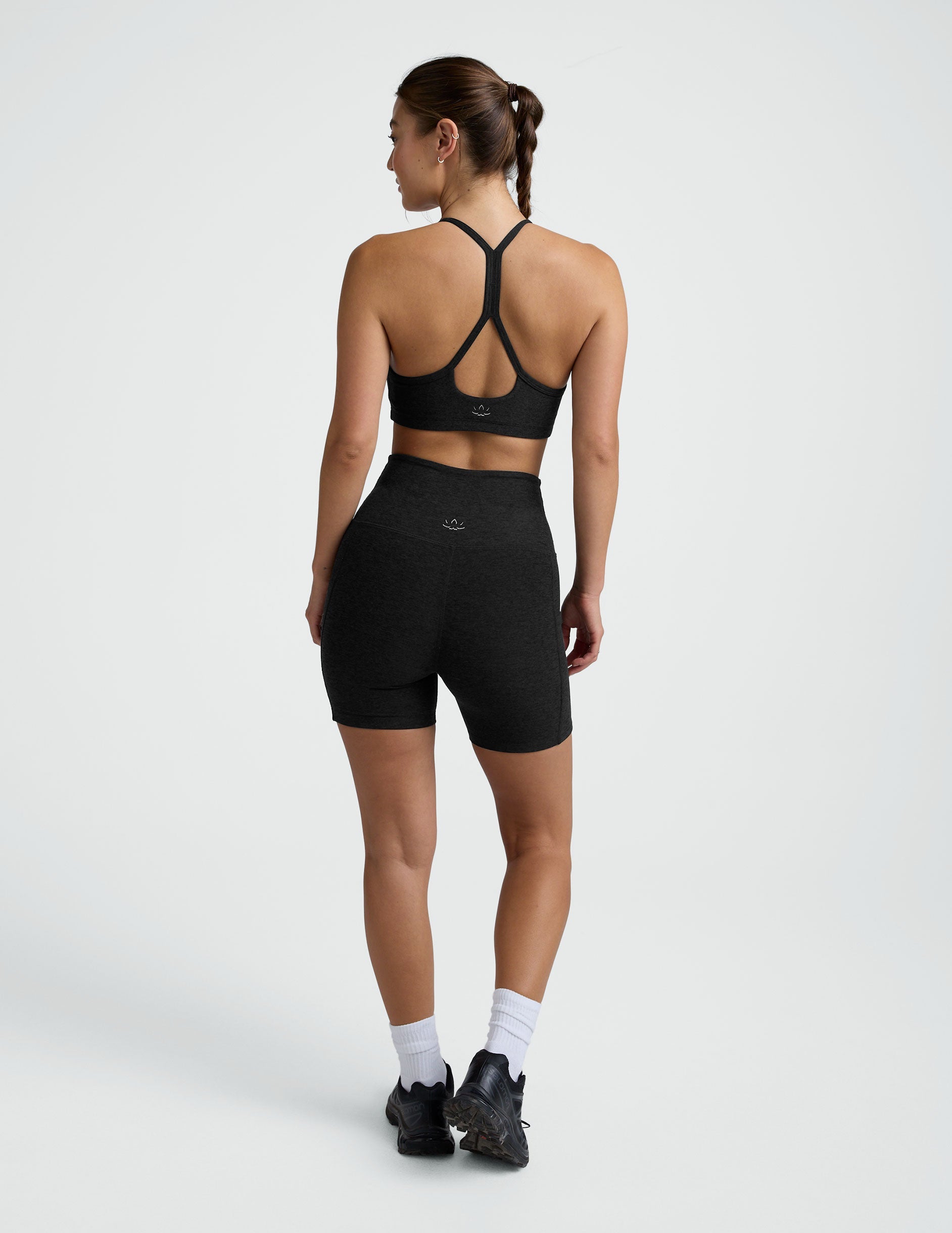 woman wearing a black sports bra and pocket biker shorts shorts on a plain background.