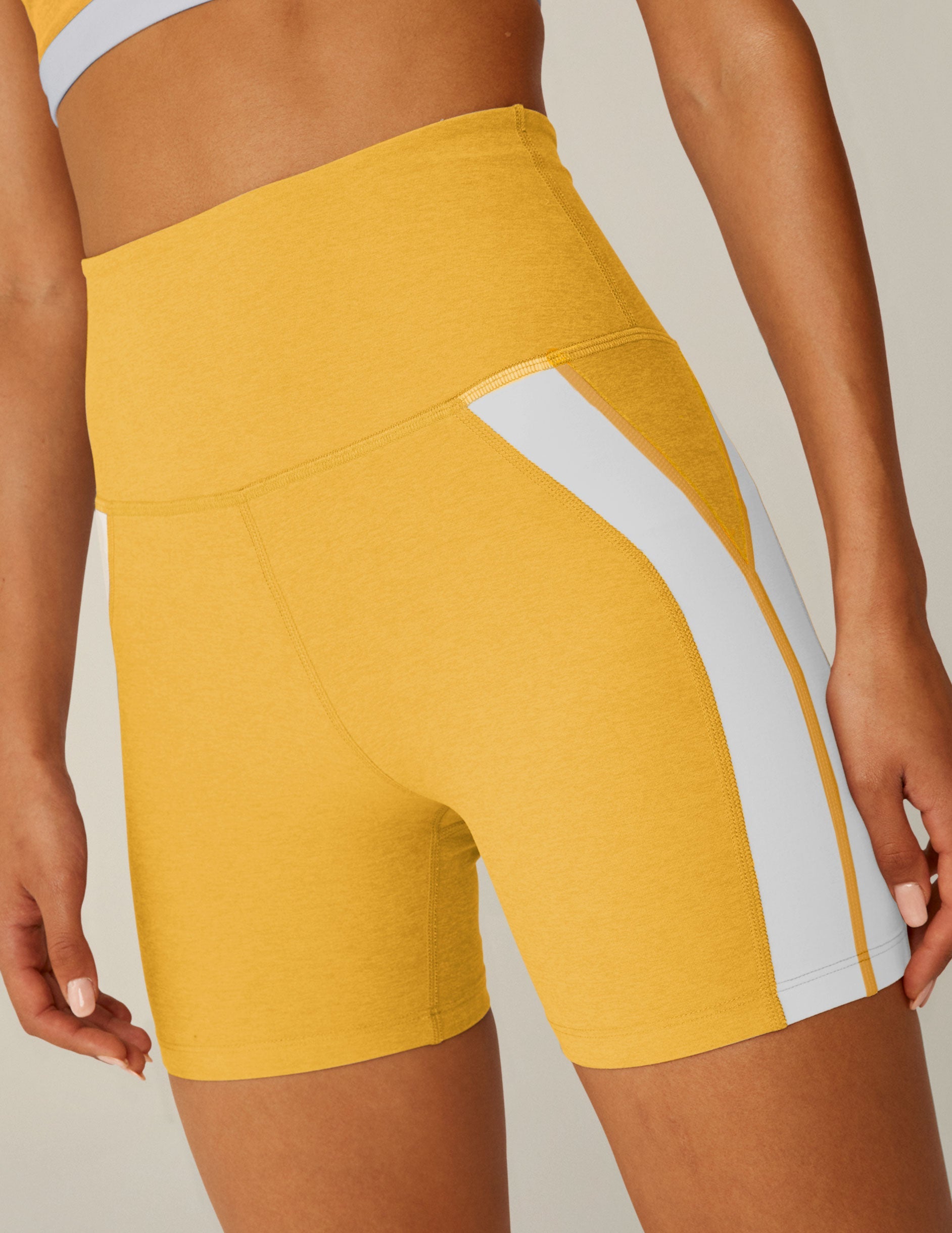 yellow high-waisted spacedye biker shorts with white lining down the sides.