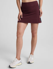 model wearing a red skirt with white and navy trim on the sides on a light gray background.