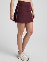 model wearing a red skirt with white and navy trim on the sides on a light gray background.