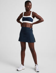 blue mid-rise skirt with white piping on sides, side slits, and built-in shorts with pockets. 