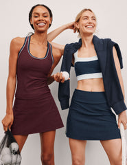 Two women in athletic wear standing together against a plain background