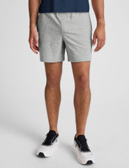 man wearing a navy t-shirt and gray shorts on a plain background.