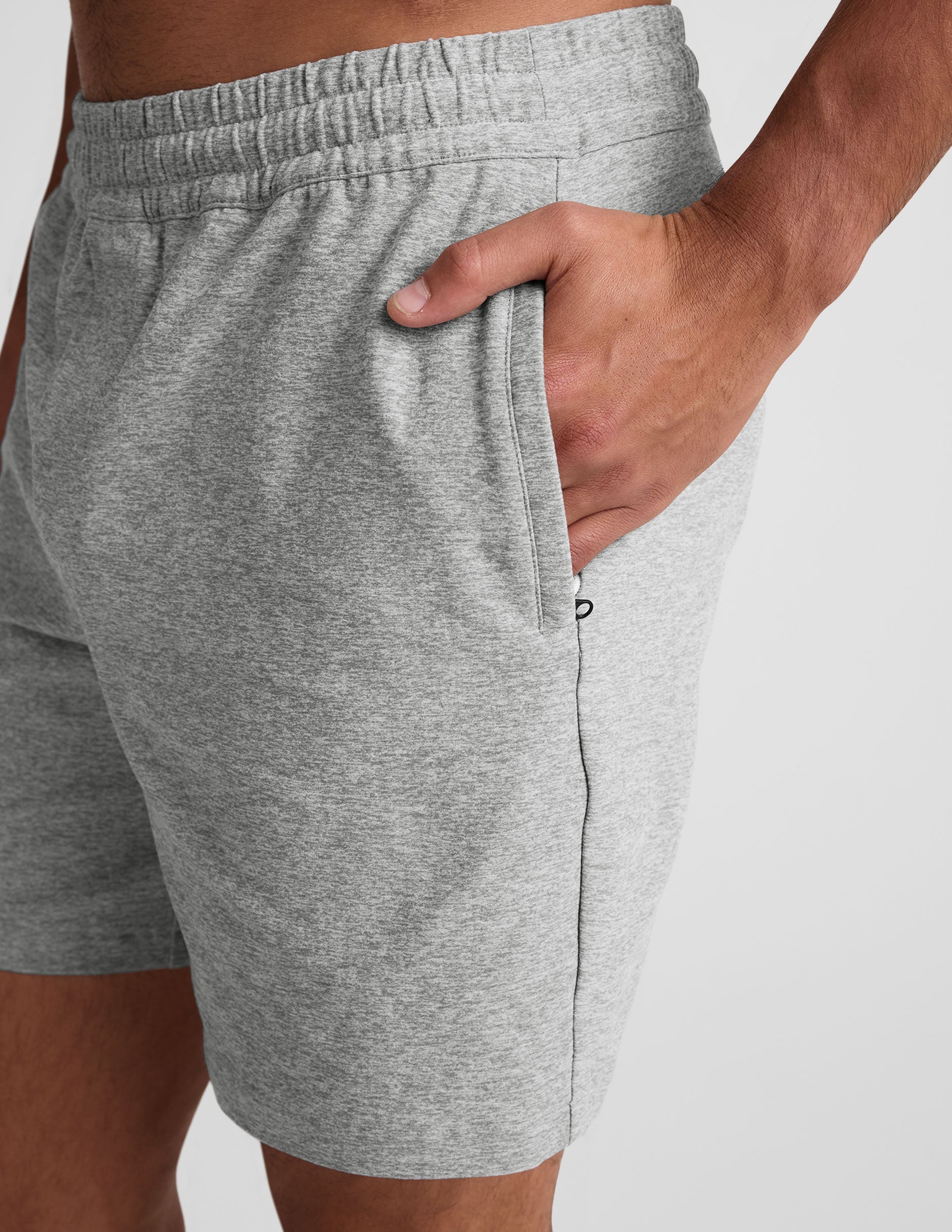 man wearing a navy t-shirt and gray shorts on a plain background.