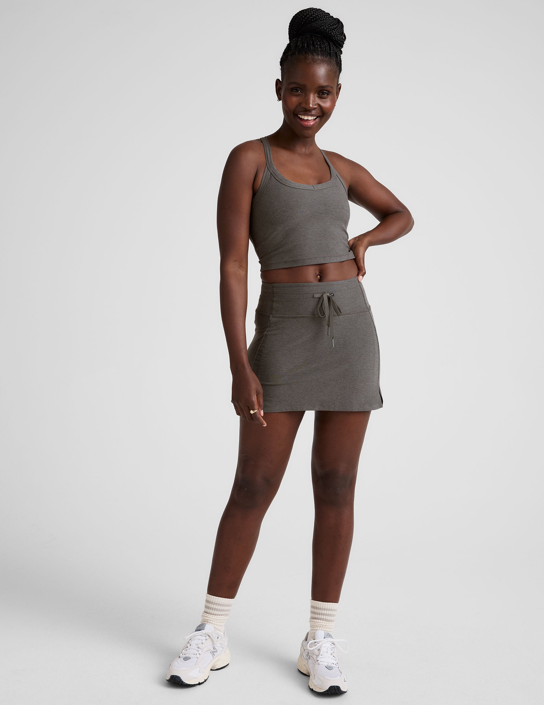 grey high-waisted mini athletic skirt with a drawstring at waistband and built-in shorts with pockets.