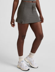 grey high-waisted mini athletic skirt with a drawstring at waistband and built-in shorts with pockets.