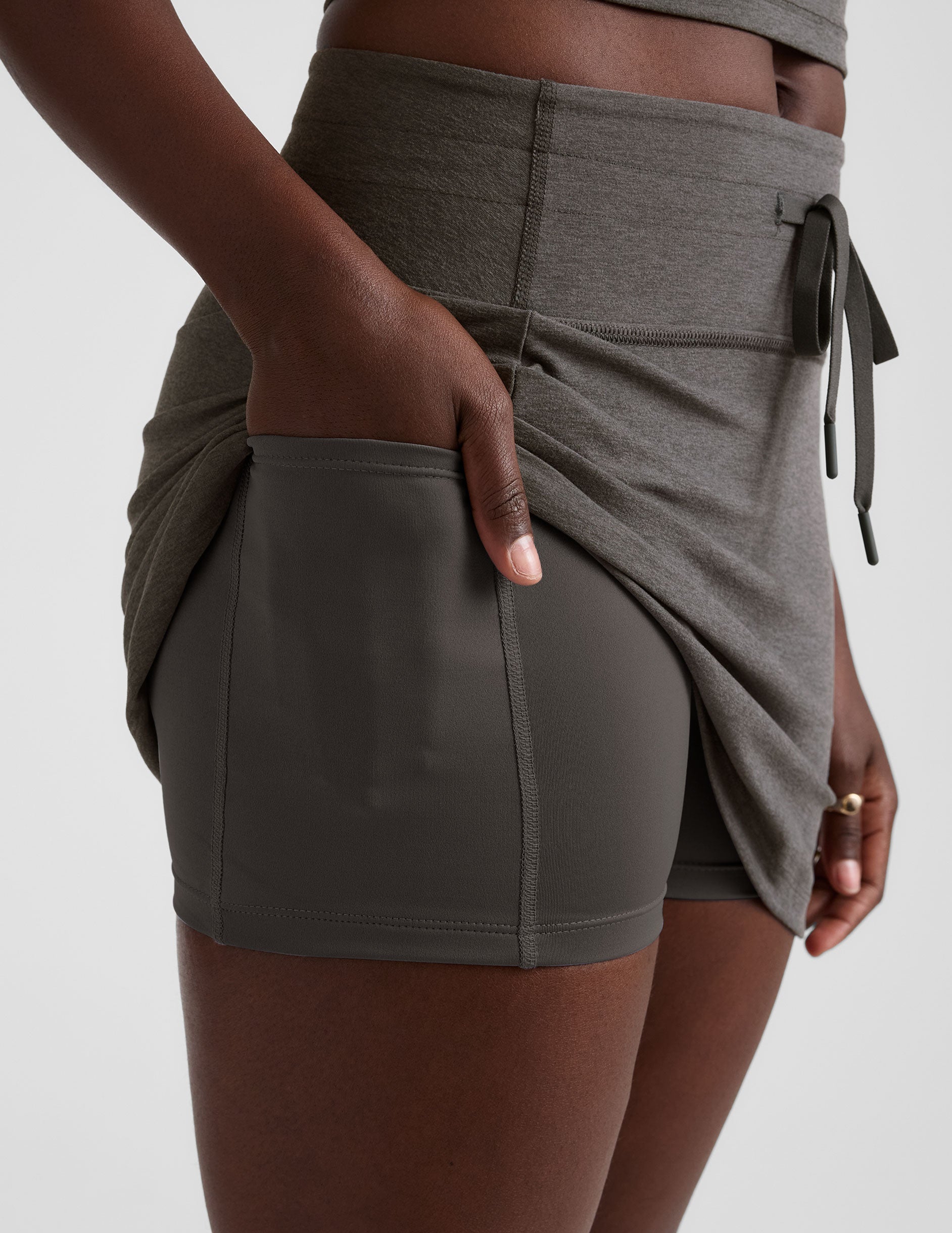 grey high-waisted mini athletic skirt with a drawstring at waistband and built-in shorts with pockets.