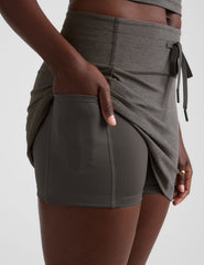grey high-waisted mini athletic skirt with a drawstring at waistband and built-in shorts with pockets.