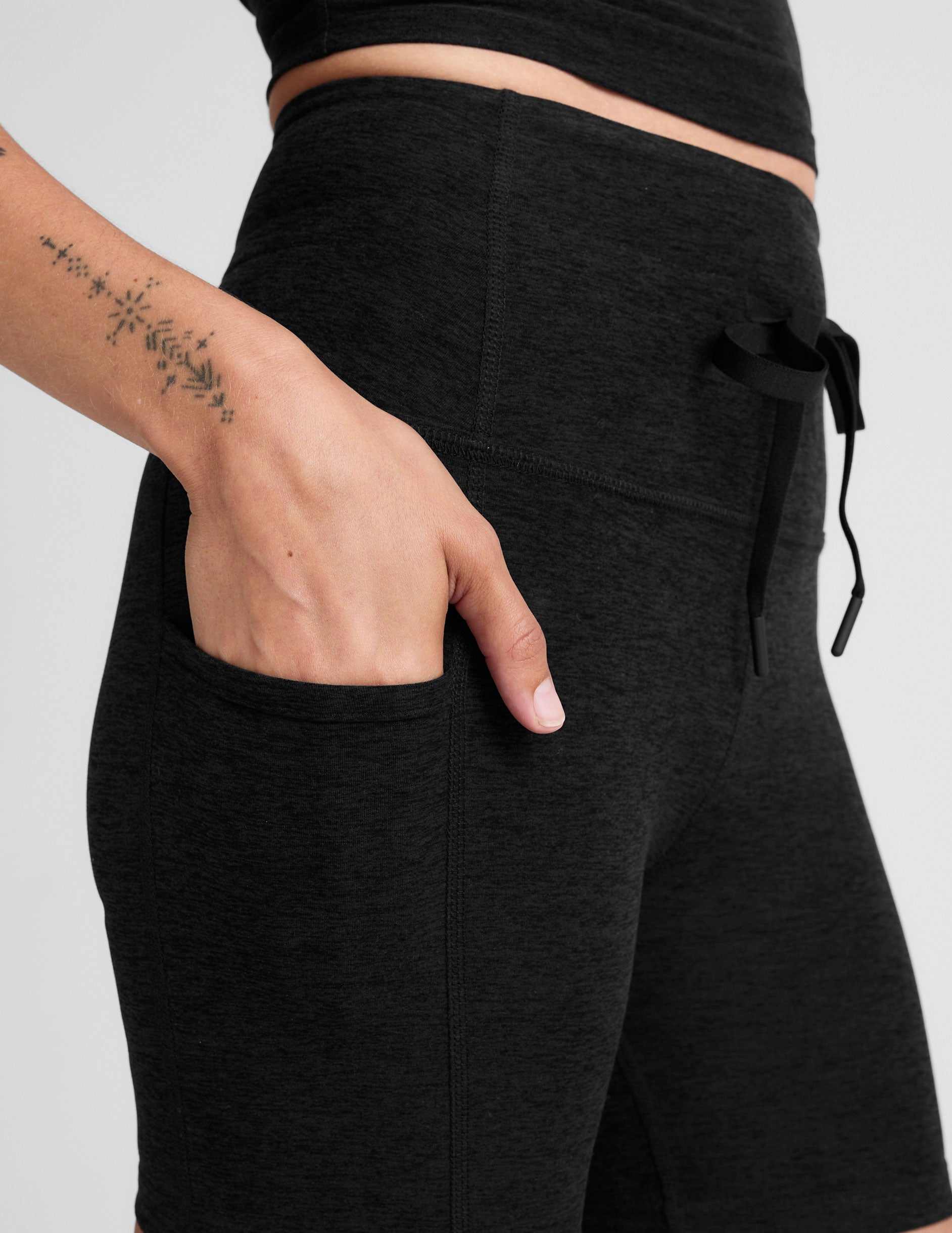 black high-waisted 5" inseam biker shorts with pockets and a drawstring at waistband. 