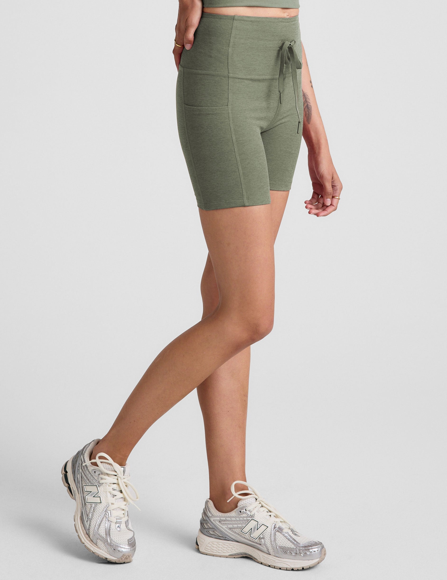 green high-waisted 5" inseam biker shorts with pockets and a drawstring at waistband. 