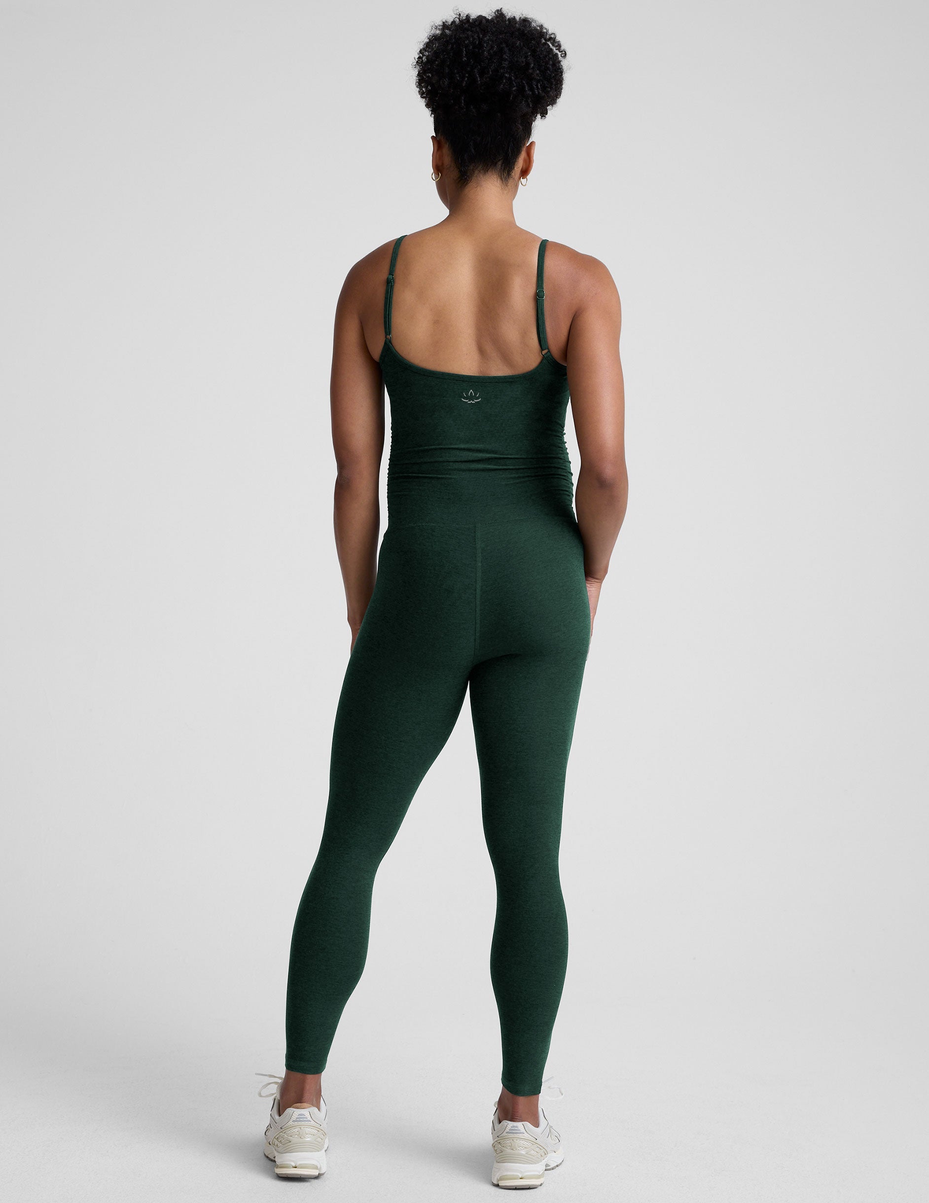 pregnant model wearing a green midi length maternity tank jumpsuit against a plain background.