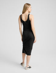 woman wearing a black maternity midi sleeveless dress on a plain background.