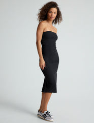 model is wearing a black midi length strapless dress with a back slit.
