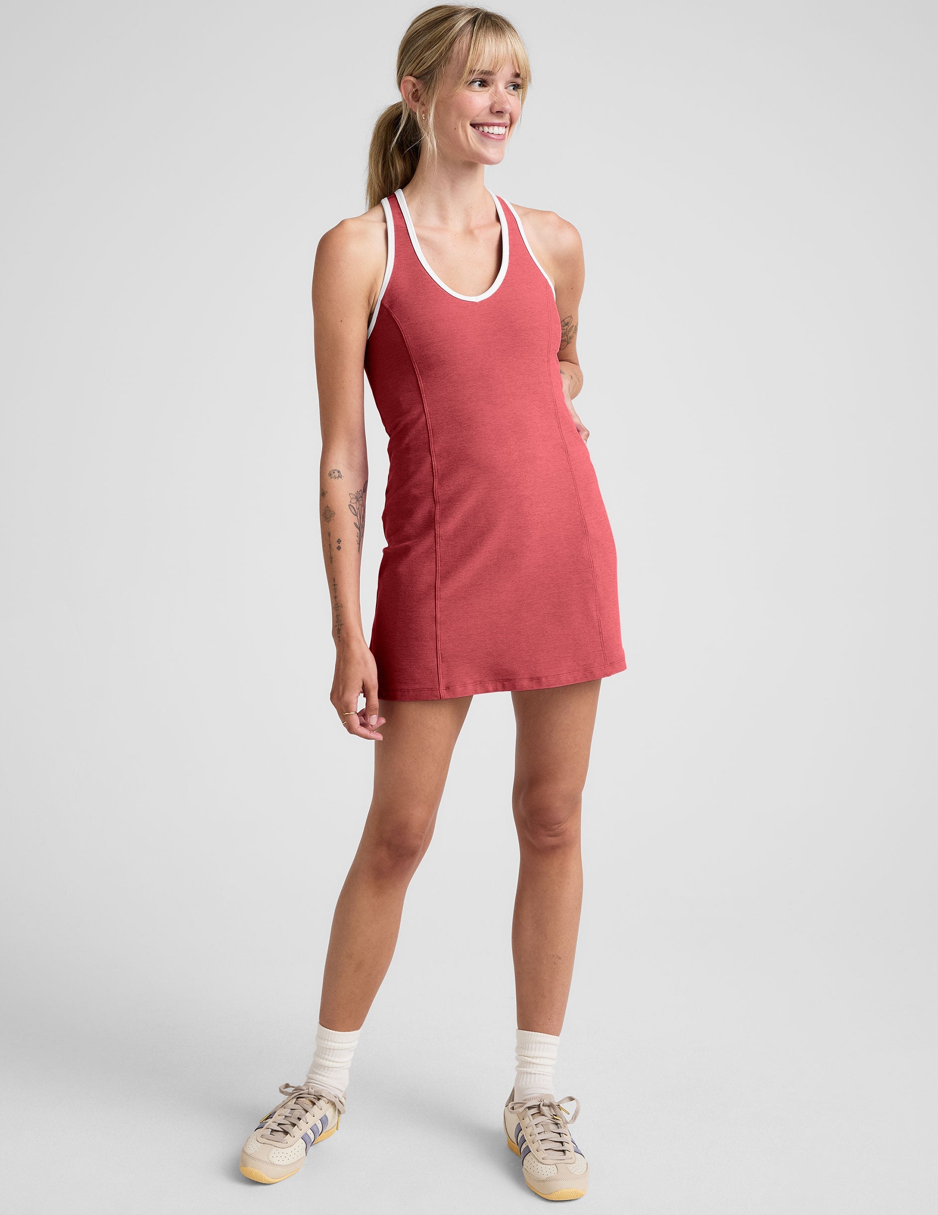 model wearing a red mini athletic dress with white contrast trim and built in shorts on a plain background.
