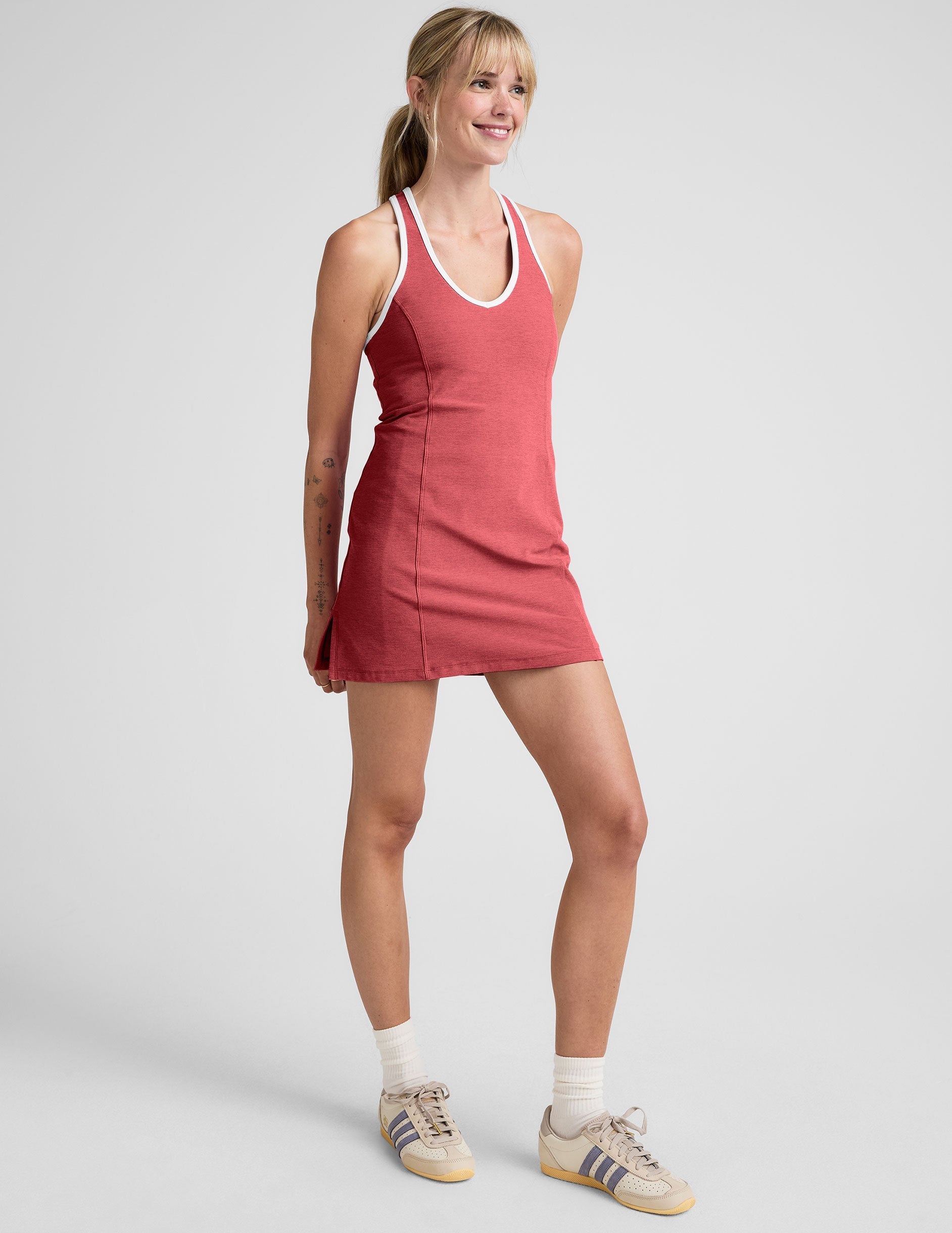 model wearing a red mini athletic dress with white contrast trim and built in shorts on a plain background.