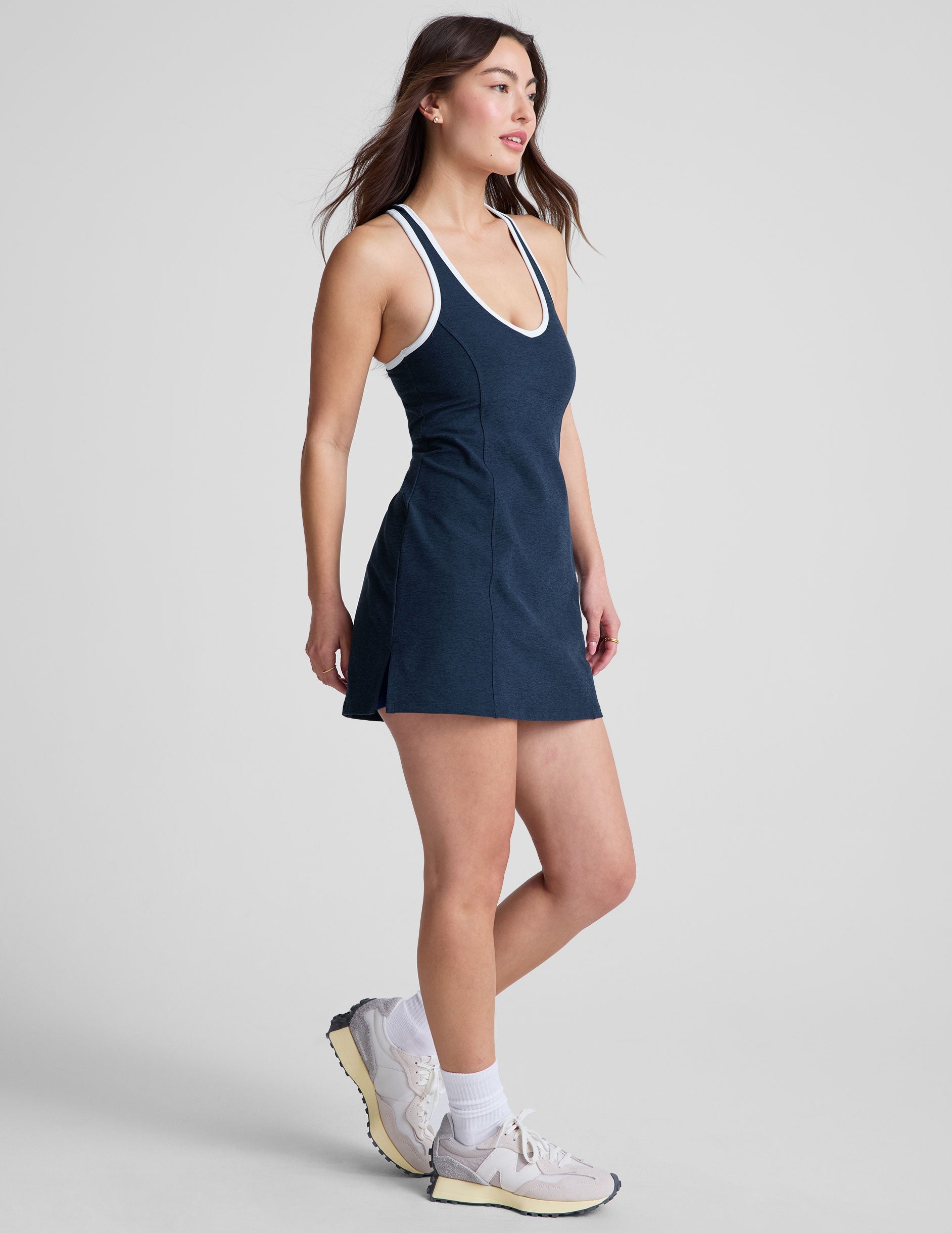 navy blue mini length dress with a front V neckline​, back keyhole detail​, contrast binding at neckline and arm openings, and an Interior bodysuit with pockets​. 