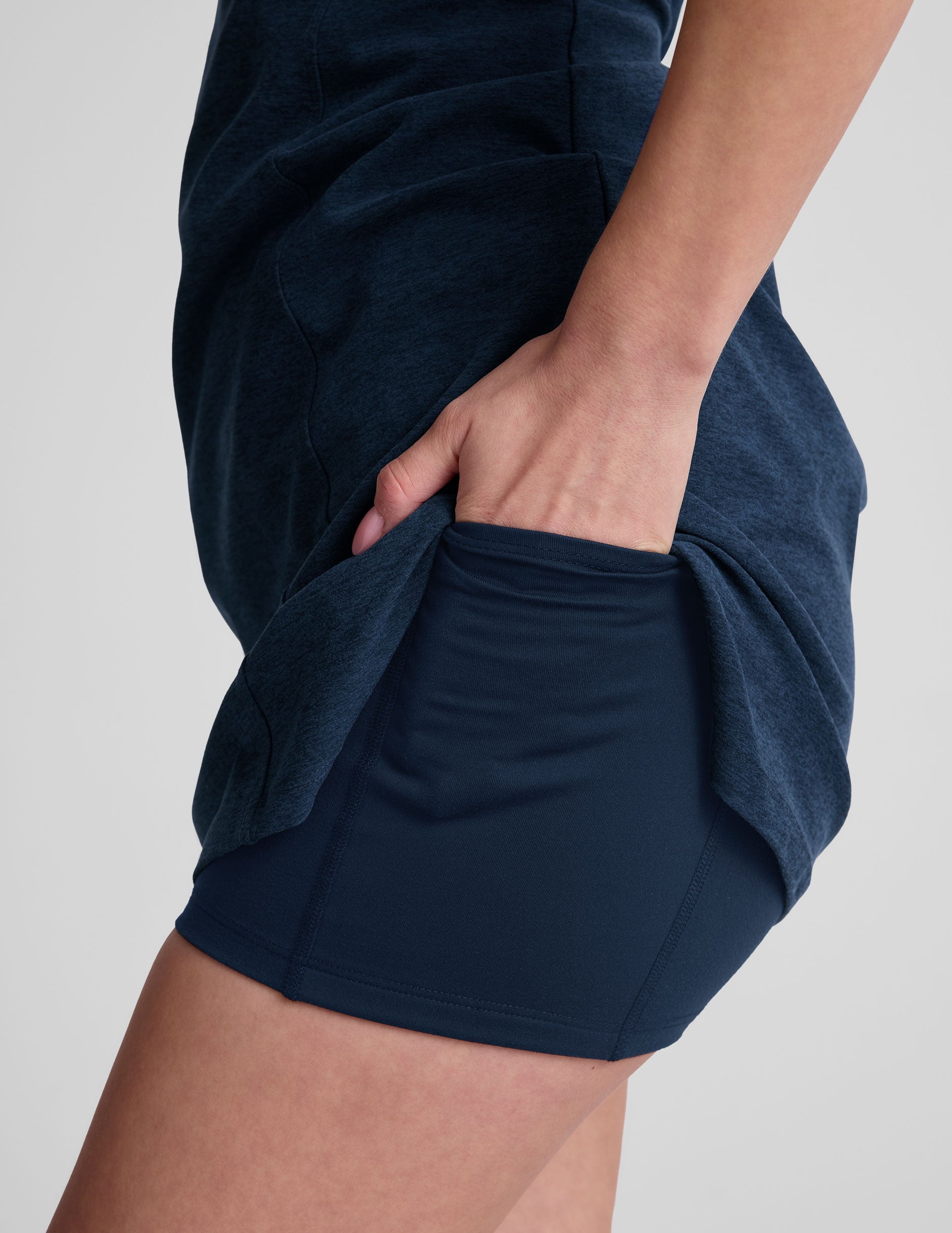 navy blue mini length dress with a front V neckline​, back keyhole detail​, contrast binding at neckline and arm openings, and an Interior bodysuit with pockets​. 