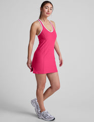 pink mini dress with a v-neckline, crossover strap detail in the back, and built-in shorts with pockets. 