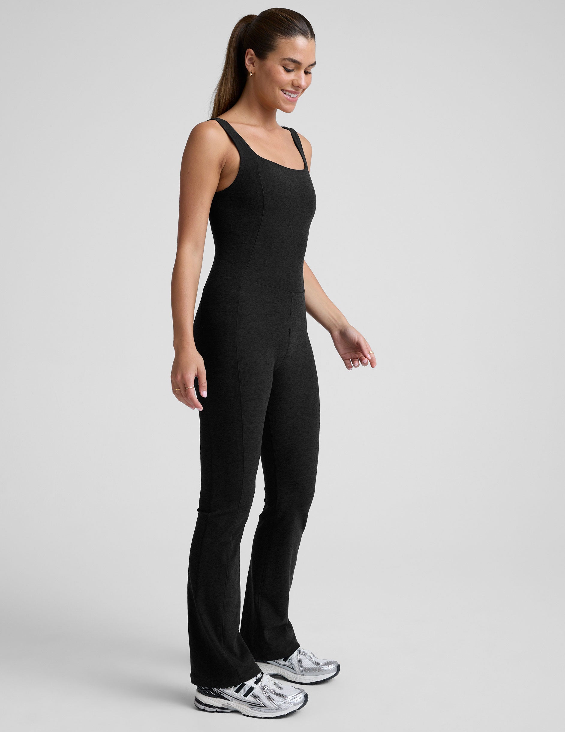 model wearing a black square neck and bootcut jumpsuit on a gray background.