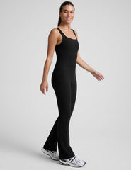 model wearing a black square neck and bootcut jumpsuit on a gray background.