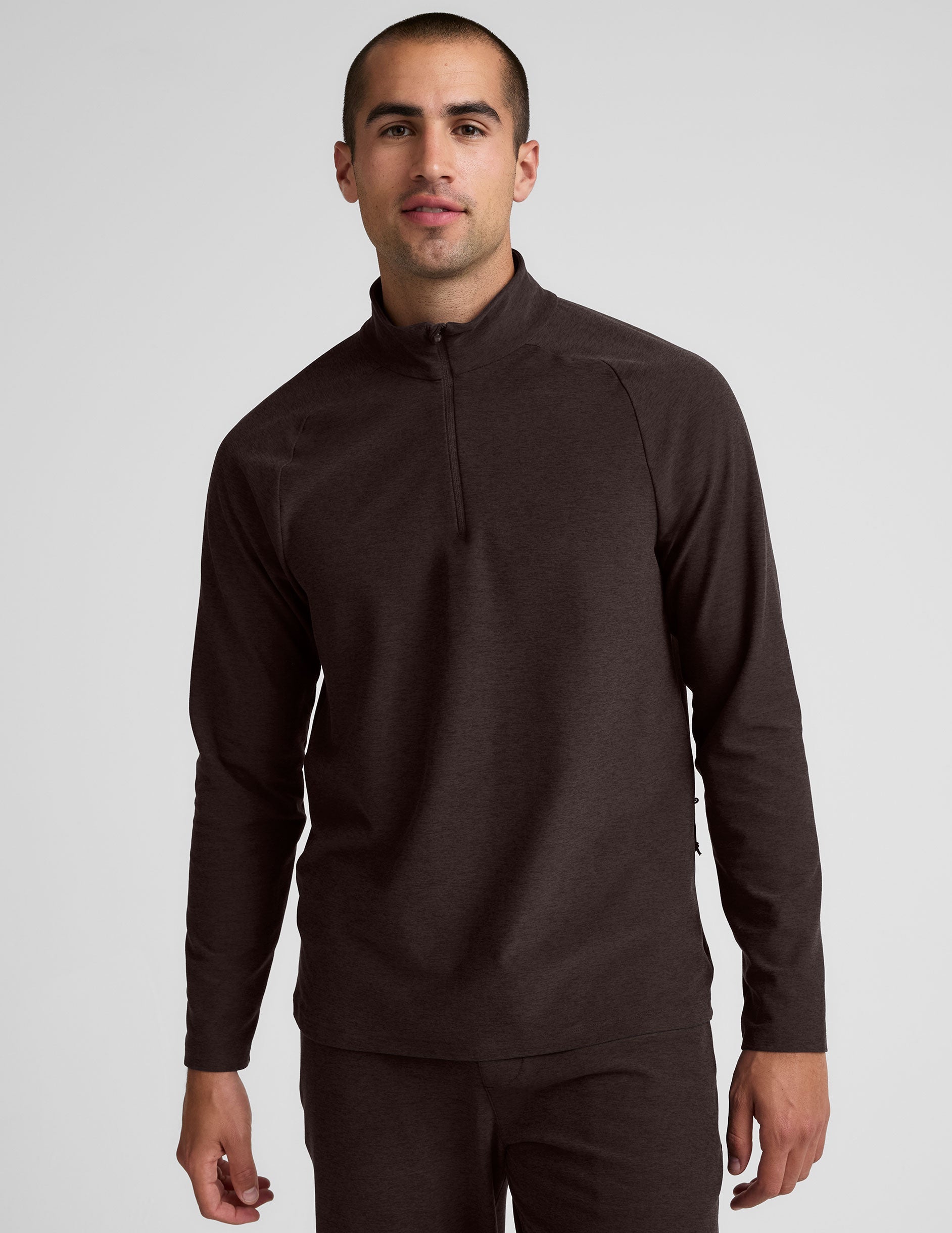 model wearing a brown men's quarter-zip pullover against a plain background.