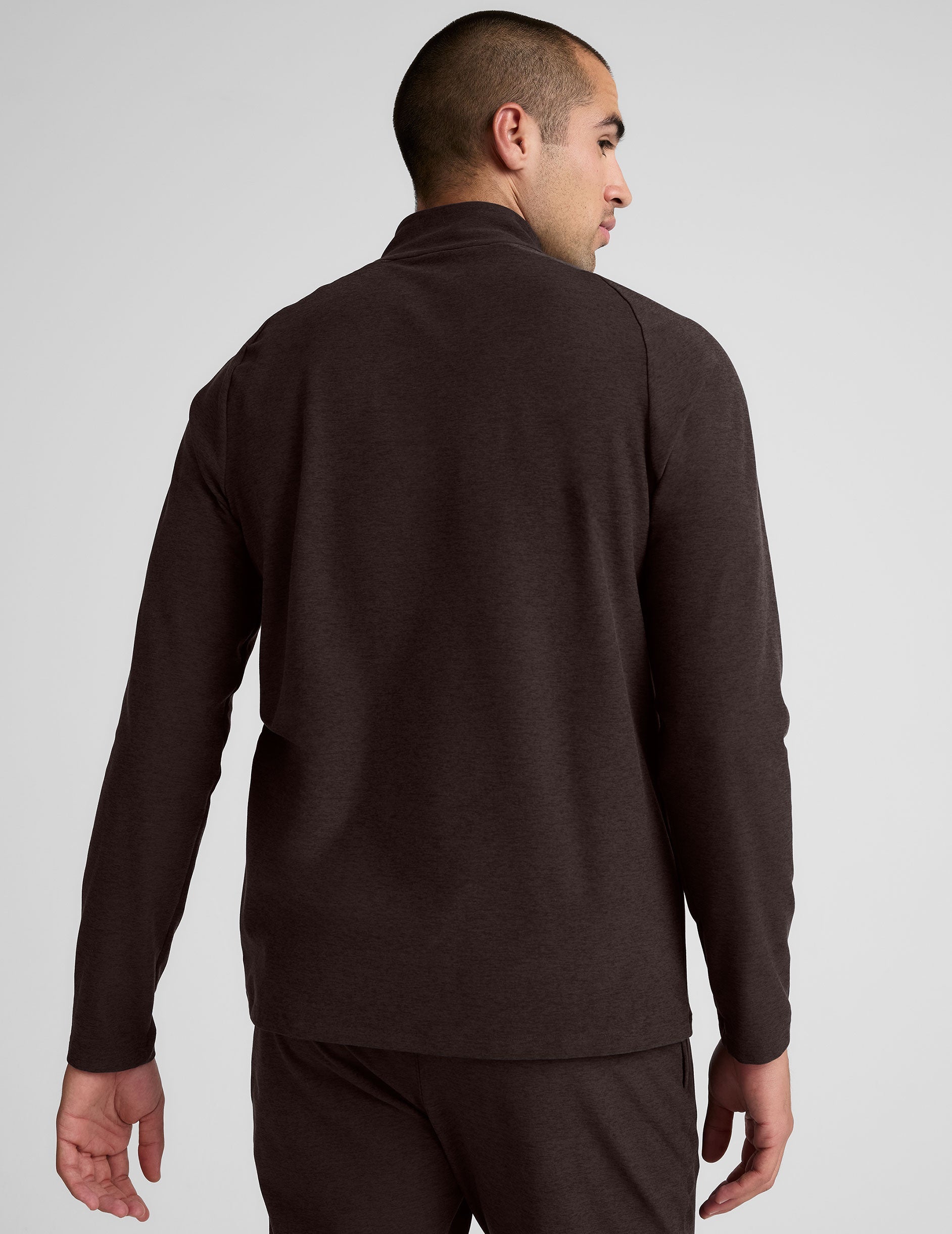 model wearing a brown men's quarter-zip pullover against a plain background.