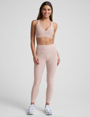 model wearing a pink v-neck sports bra and leggings on a plain background.