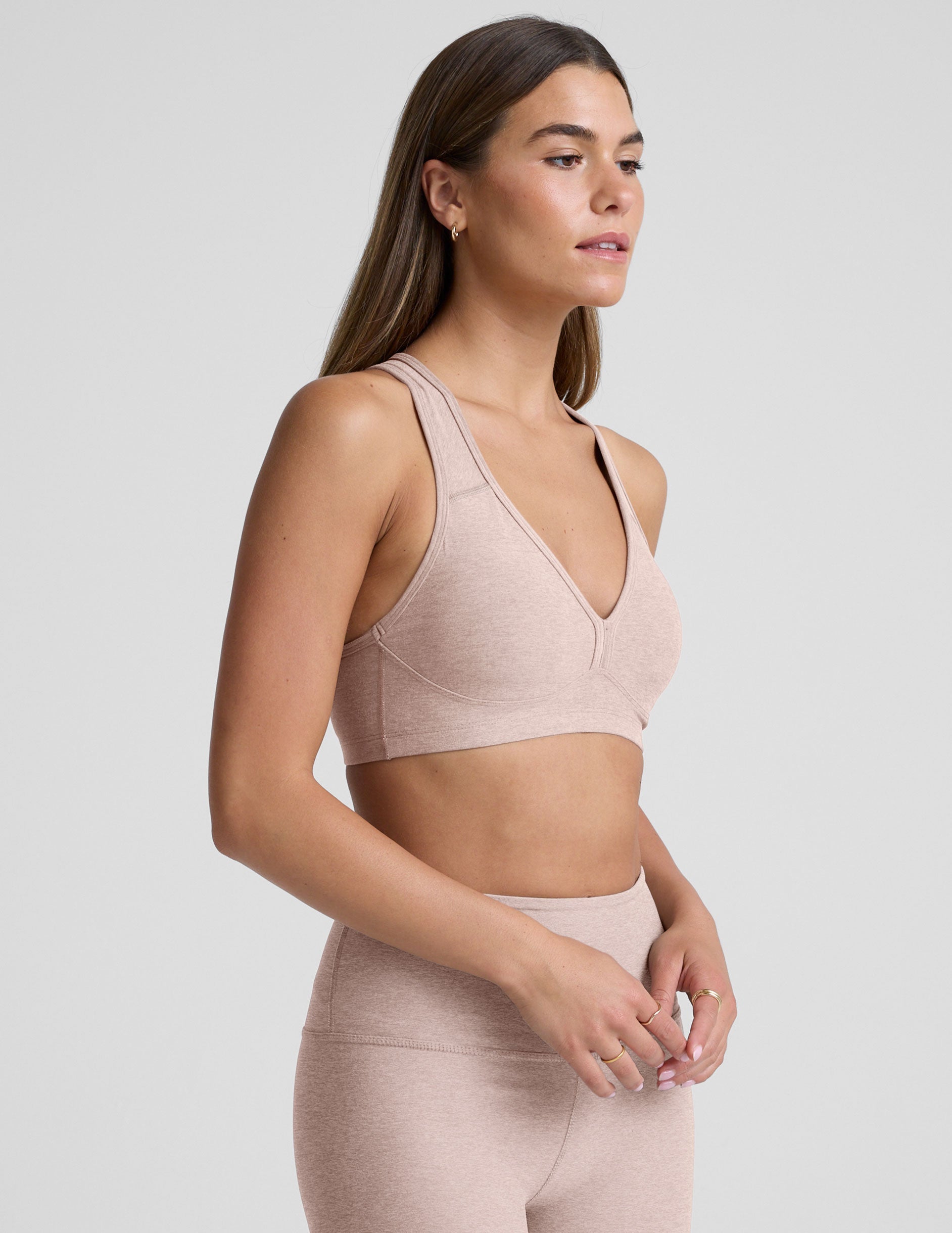 model wearing a pink v-neck sports bra and leggings on a plain background.