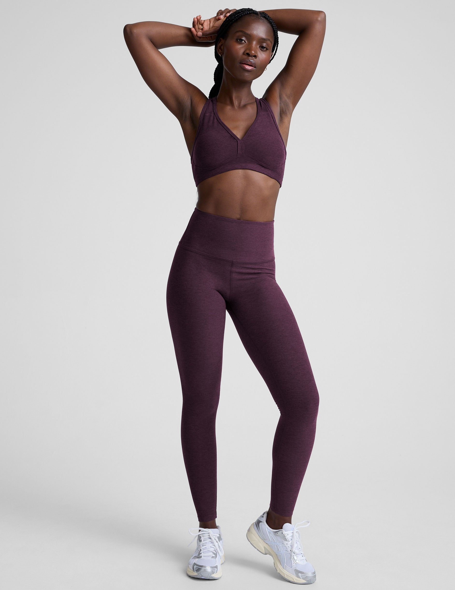 model wearing a purple soft v-neck racerback sports bra and leggings on a plain background.