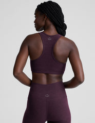 model wearing a purple soft v-neck racerback sports bra and leggings on a plain background.
