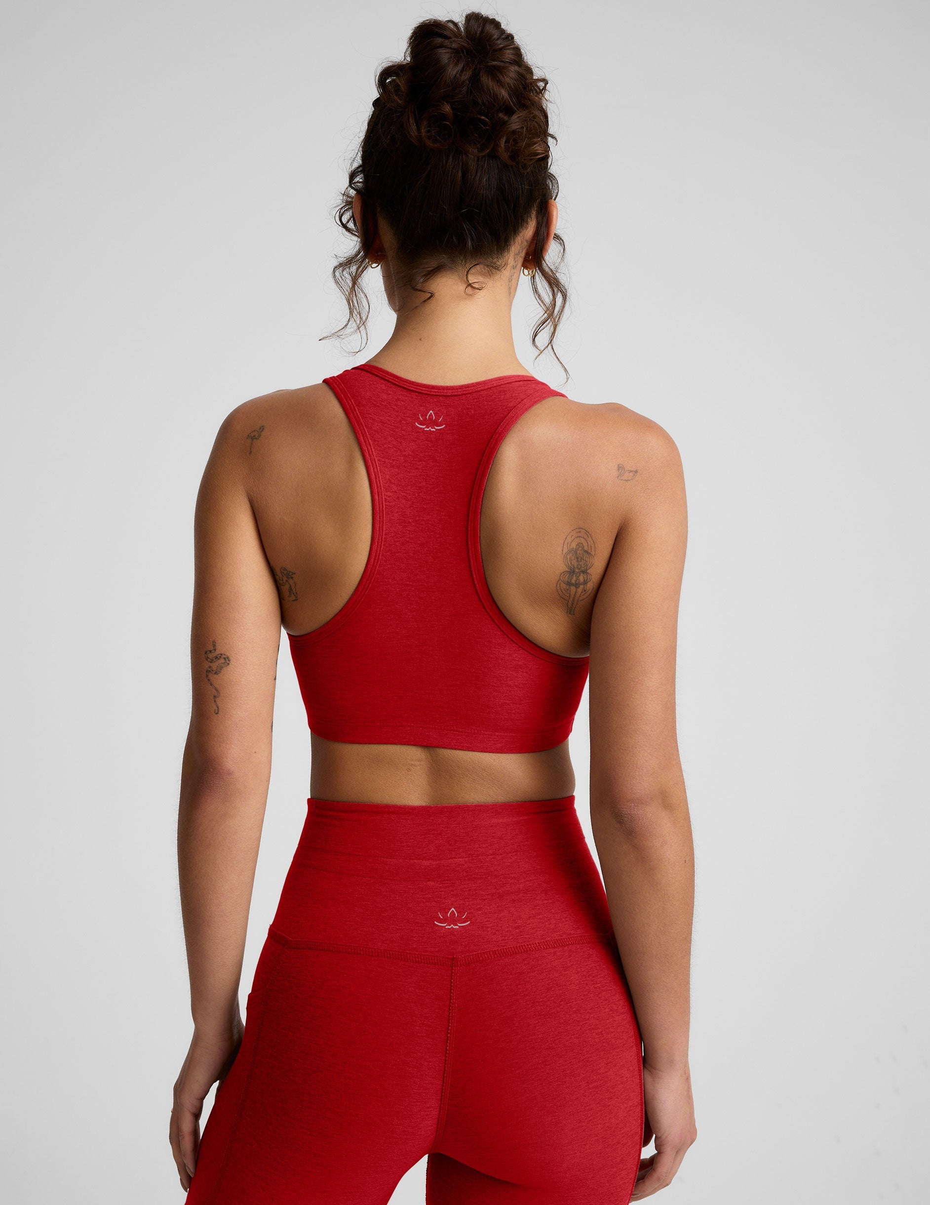 Woman wearing a red v-neck bra and leggings on a light background.