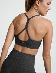 person wearing a black-charcoal slim racerback bra with matching leggings against a plain background.