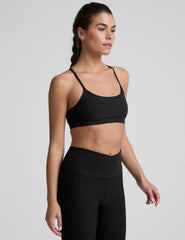 woman wearing a black slim racerback bra and leggings on a plain background.