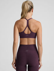 model wearing a purple slim strapped racerback bra and leggings on a light gray background.