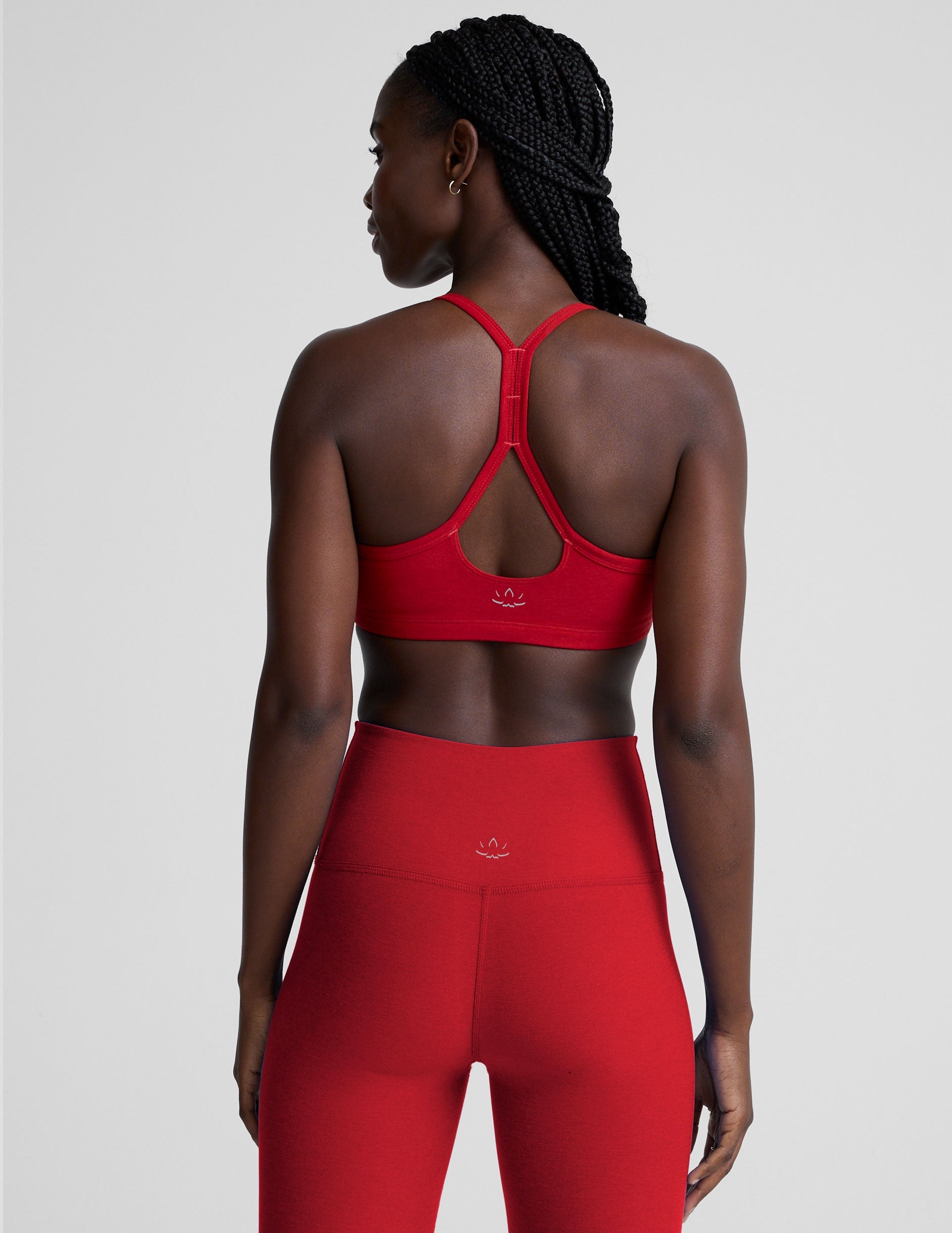 Woman wearing a red sports bra and leggings on a light background.