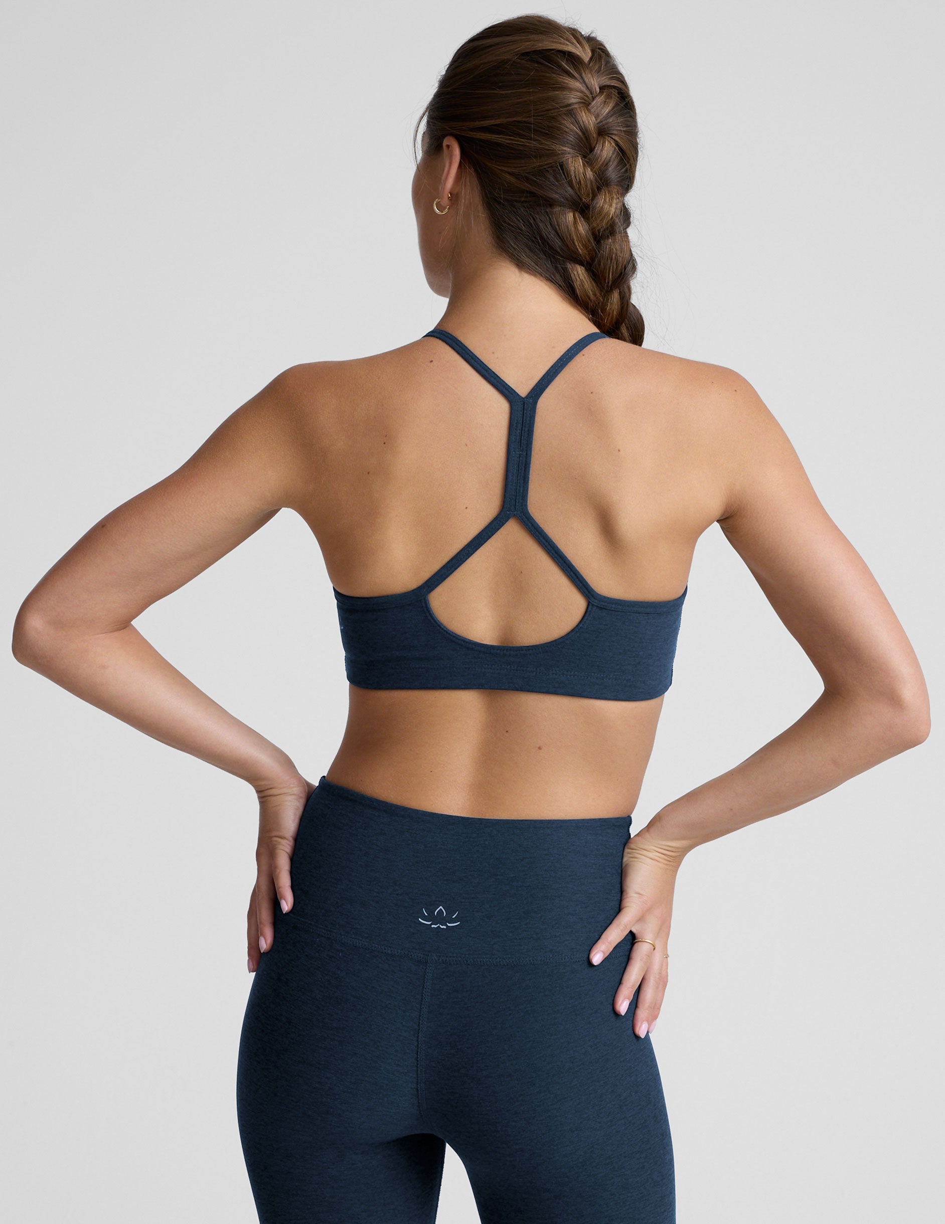 person wearing a blue slim racerback bra with leggings against a plain background.