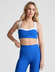 blue self-lined, medium to low support bra top with a colorblock sweetheart neckline panel​, contrast straps, and princess seams. bra is paired with blue high-waisted midi leggings. 