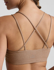 model wearing a brown sports bra with overlapping back straps and leggings on a white background.