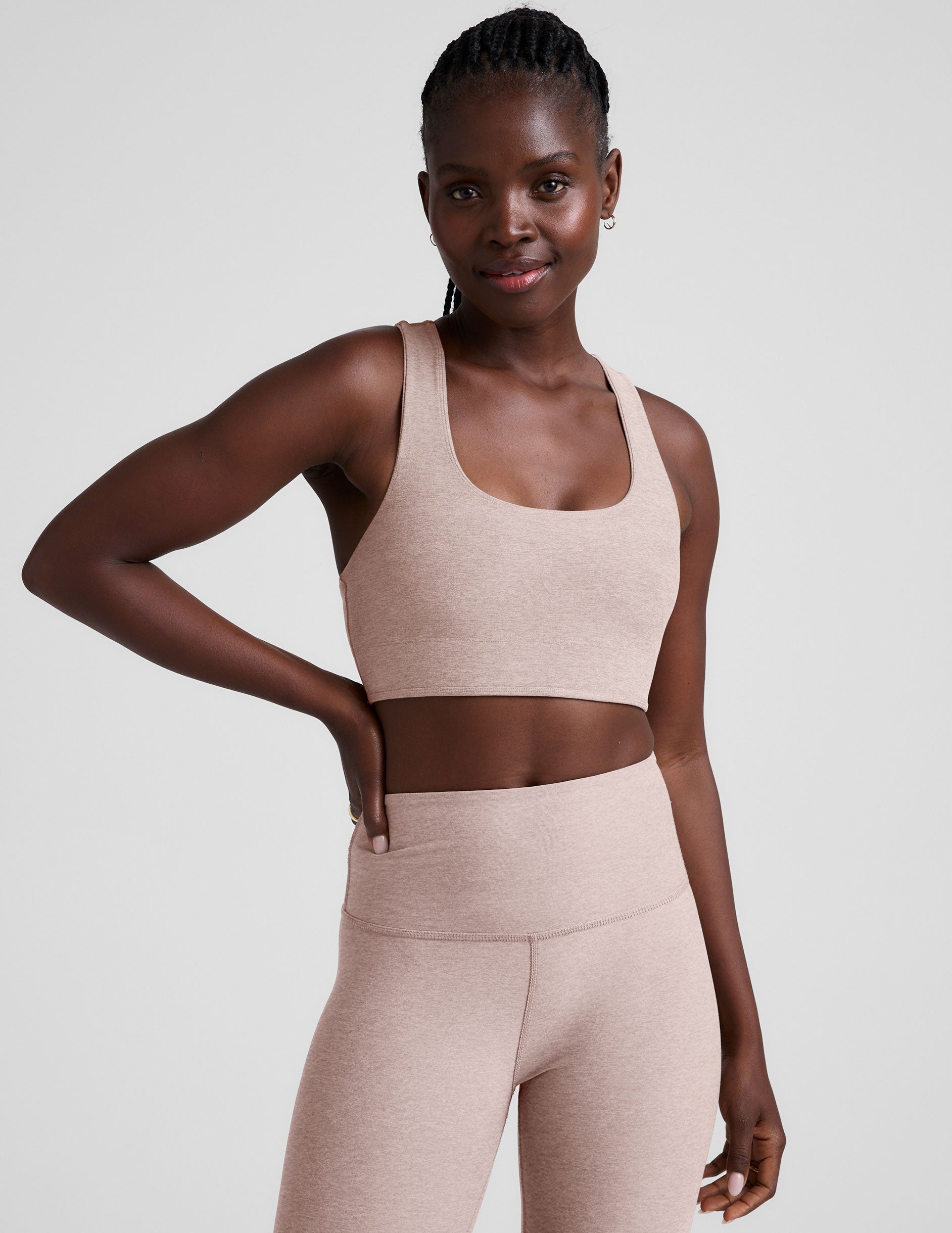 model wearing a pink scoop neck racerback long line sports bra and leggings set on a light gray background.