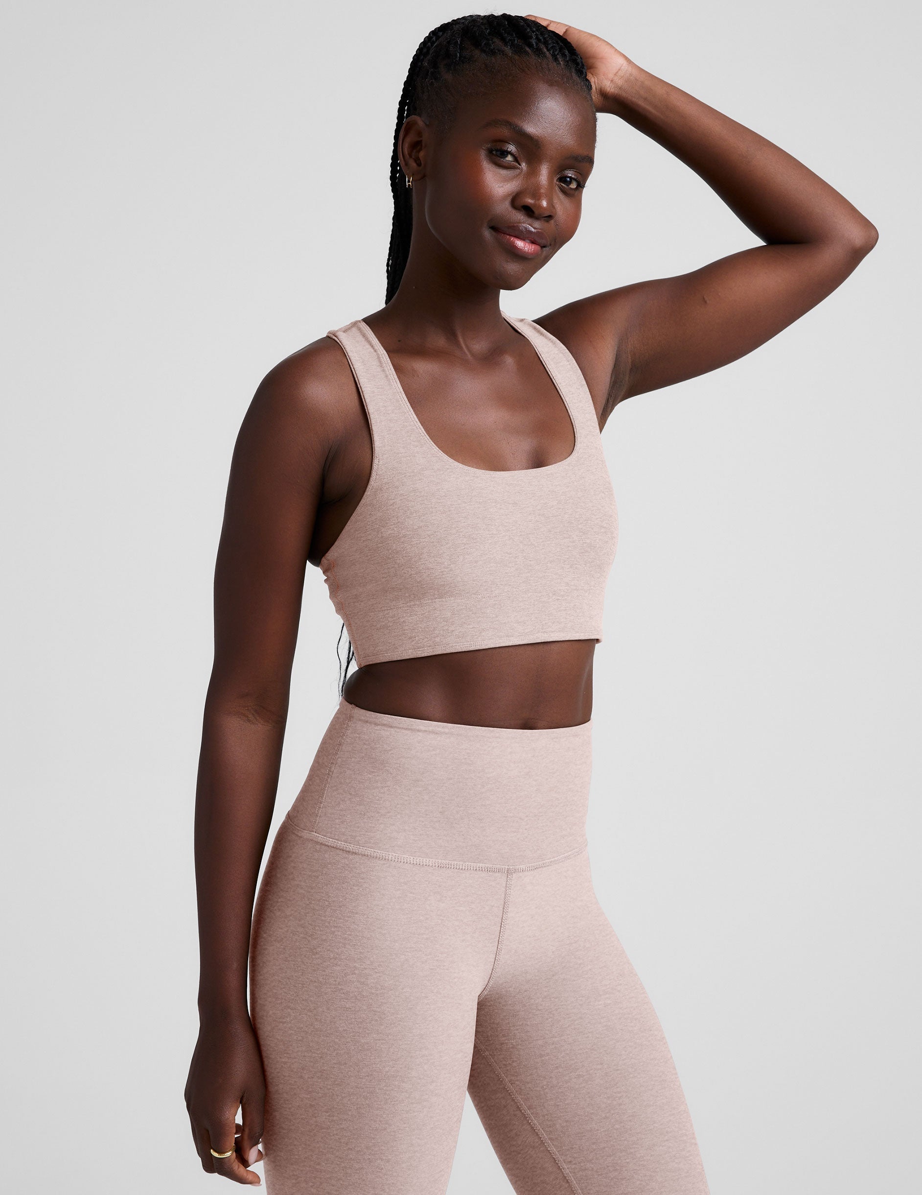 model wearing a pink scoop neck racerback long line sports bra and leggings set on a light gray background.
