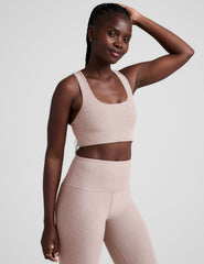 model wearing a pink scoop neck racerback long line sports bra and leggings set on a light gray background.